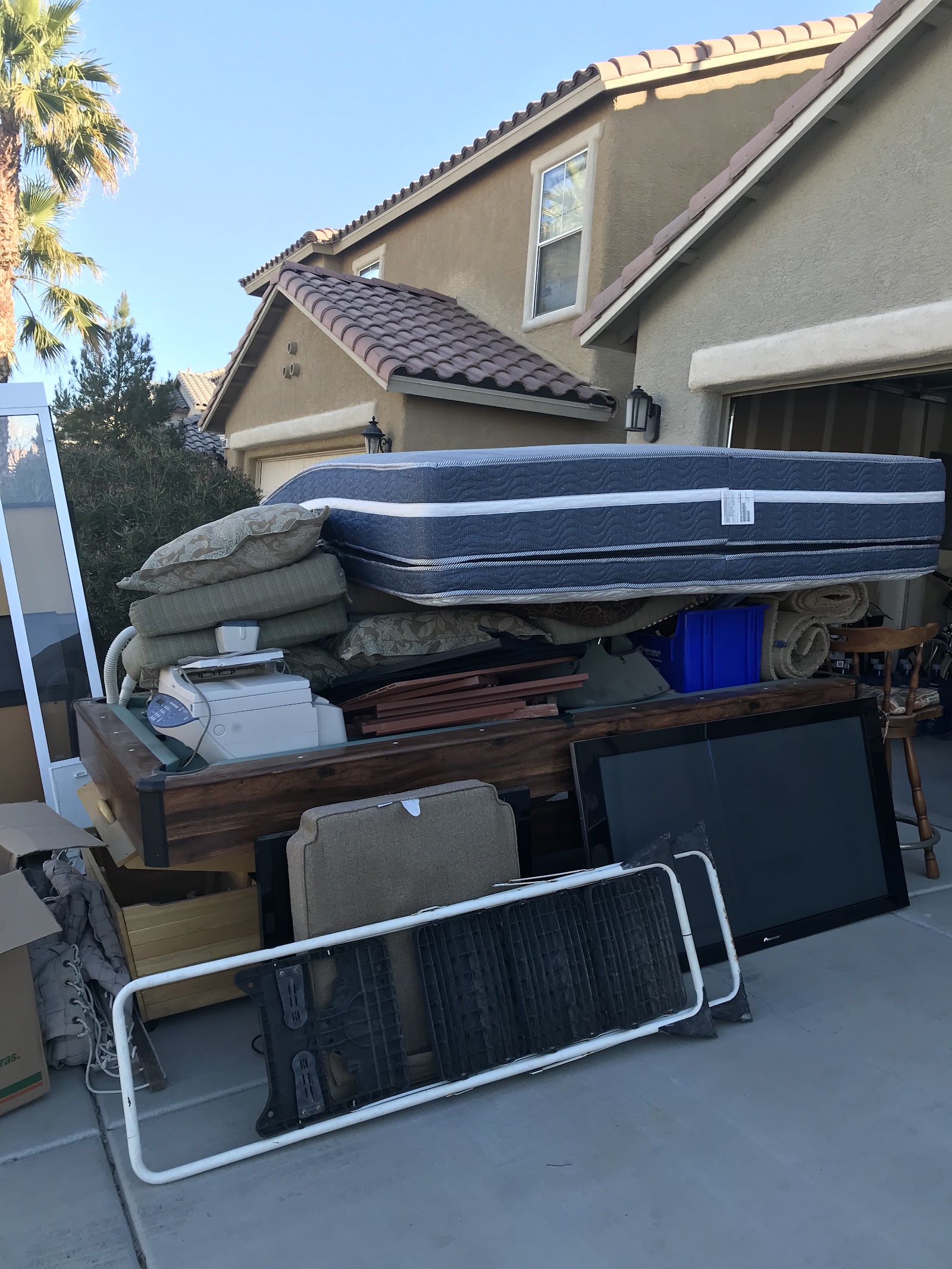 Driveway pile of mattress, furniture, electronics, and household junk staged for pickup